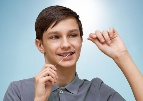 boy with braces flossing