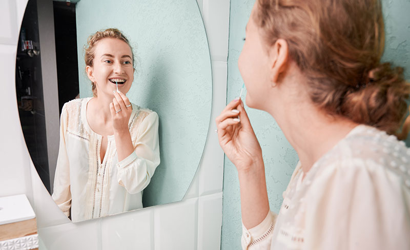 girl with braces using an interdental brush in her bathroom