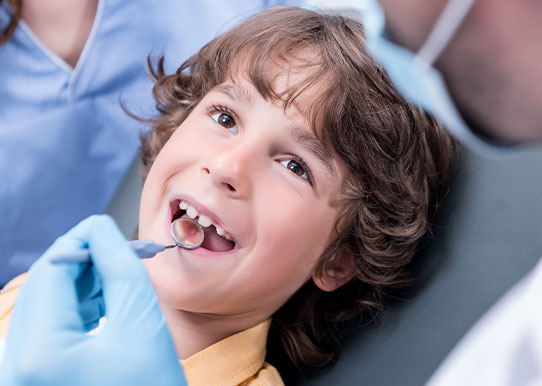 orthodontist looking into a happy cihld's mouth